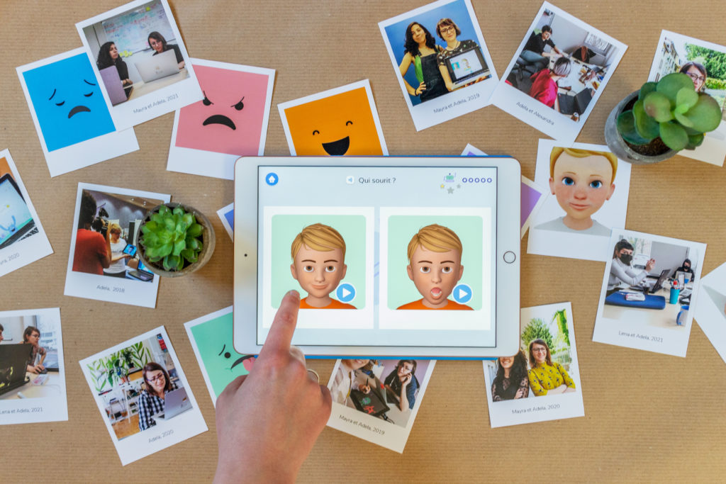 Un doigt appuie sur le jeu de l'application Emoface & Learn Emotions pour tablettes